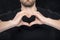 Man in a black shirt showing hand gesture heart