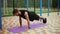 Man in black sportswear doing push ups on mat with football field on background