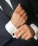 A man in a black suit straightens his cufflinks