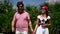 Man and blind woman are walking in park, holding hands, boyfriend is helping to girlfriend