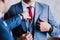 A man in a blue business suit straightens his friend`s tie