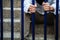 A man in blue collar shirt and black slacks behind the iron fence, Hand holding iron fence with a sense of hopelessness, sadness