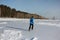 Man in a blue jacket running across the ice of a frozen river, O