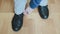 Man in a blue jacket and white trousers adjusts his pant leg