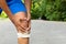 Man with blue runing shorts use hands hold on his knee after running on road in morning time with copy space for text or design