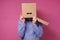 Man in blue shirt with a brown paper box on his head, hiding from job stress.