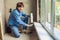 Man in a blue shirt does window installation. Using a mounting foam