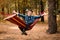 Man in blue shirt and hands up relax in hammock in forest