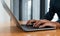 Man in blue shirt typing on laptop in office