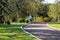 A man in a blue shirt walking his dogs down a long smooth winding footpath in the park