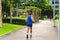 A man in a blue singlet and black shorts jogs at a park in the middle of the city. Morning scene in Fort Bonifacio, Philippines.