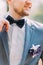 Man in blue suit with black bow tie, flower brooch, and classic texture pocket square, close up