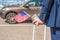 Man in a blue suit with a suitcase flag and american passport at the airport parking on the backdrop of his car. Business trip