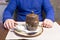 A man in a blue sweatshirt opens a brown pot with food. Close-up