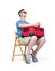 Man in a blue T-shirt, shorts and sunglasses sits on a chair with a red suitcase waiting. Isolated on white background