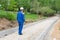 A man in a blue uniform is standing and looking at an unfinished road