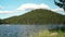 Man with a boat rowing in the calm waters of a mountain lake on a sunny summer day with blue sky, Bulgaria