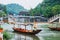 Man in a boat with a traditional triangular chinese hat standing in waters of Tuo river flowing through the centre of ancient city