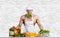 Man bodybuilder in white toque blanche and cook protective apron cooking cottage cheese and vegetables