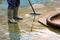 Man in boots cleans after the summer season the bottom of the fountain