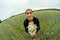 A man with a bouquet of daisies field stands in the middle of a wheat field