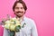man with a bouquet of flowers waiting on a date staying on pink background