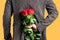 Man with a bouquet of red roses behind his back. Elegant man holding red rose flowers in hand