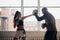 A man with boxing paws on his hands teaches the technique of hitting a novice girl in a light gym