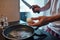 Man breaking egg with knife on pan during cooking