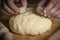 Man breaks a stick of brewer`s yeast on top of the bread dough