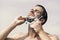 Man with bristle on clear sky background. Macho shaving chin with razor on clear sky background