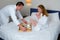 Man brought breakfast tray to hotel room and placed it on bed next to woman.