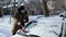 A man brushes a car windshield from snow. In winter, the car was covered with snow