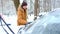 A man brushes snow from a car after a snowfall. A hand in a mustard jacket with a car broom on the white body. Winter weather cond