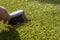 Man brushing rubbish on artifiicial grass turf with a hand brush in sunshine.