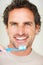 Man brushing teeth. Closeup of mature man holding toothbrush and smiling.