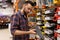 a man builder at a hardware store chooses a hacksaw for wood next to a rack with a tool for woodworking