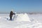 Man building an igloo of snow blocks on a glade