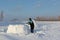 Man building an igloo of snow blocks in the winter