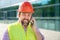 A man building inspector in a construction helmet answers phone call