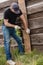 A man builds and paints a fence from rough boards