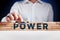 Man builds a structure of wooden blocks with the word power. Building power in business or politics