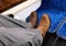 Man bus passenger in wet dirty boots puts his muddy feet on seat opposite. The seats already are stained with mud