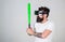 Man with bushy beard and tattoo holding green bat. Hipster with trendy beard and mustache doing sports. Bearded man in