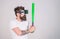 Man with bushy beard and tattoo holding green bat. Hipster with trendy beard and mustache doing sports. Bearded man in