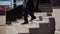 Man in business blue suit walks down the stairs outside. Legs in classic boots.