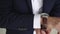 A man in a business suit dress watches on hand. Businessman button clock hands on close-up.