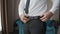 A man in business suit hands tightens belt at waist