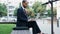 Man in business suit typing on the laptop outdoor of his office in the city