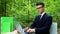 Man of business working on laptop in park, sitting at desk, air conditioning